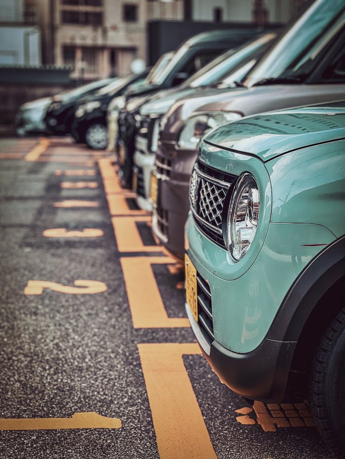 A row of parked cars in an urban parking lot with numbered spaces, showcasing a focus on one green car.